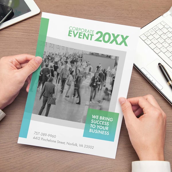 Full color flyer held in hands showing a professional event design with business information and modern layout